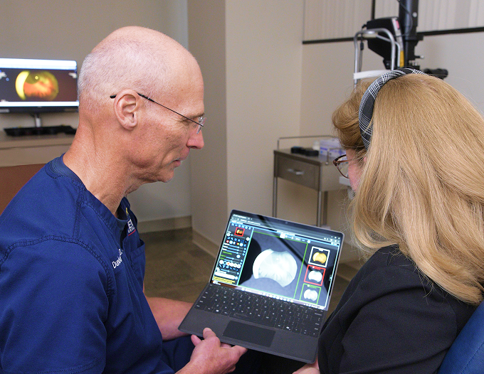 Ophthalmologist reviewing retinal imaging results on a laptop with a patient.